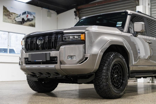 2025 Toyota Land Cruiser Prado VX in Titanium Silver with lift kit fitted with ROH Lotus Matt Black 18x9 ET40 alloy wheels and A/T tyres — front fascia close-up at Ute Nation