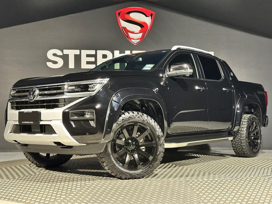 2024 Volkswagen Amarok V6 4Motion dual cab in Deep Black Pearl with flared arches fitted with Covert RV3 Matt Black alloy wheels and Delium Terra Raider A/T tyres — front three-quarter view at Stephen Hill Motors